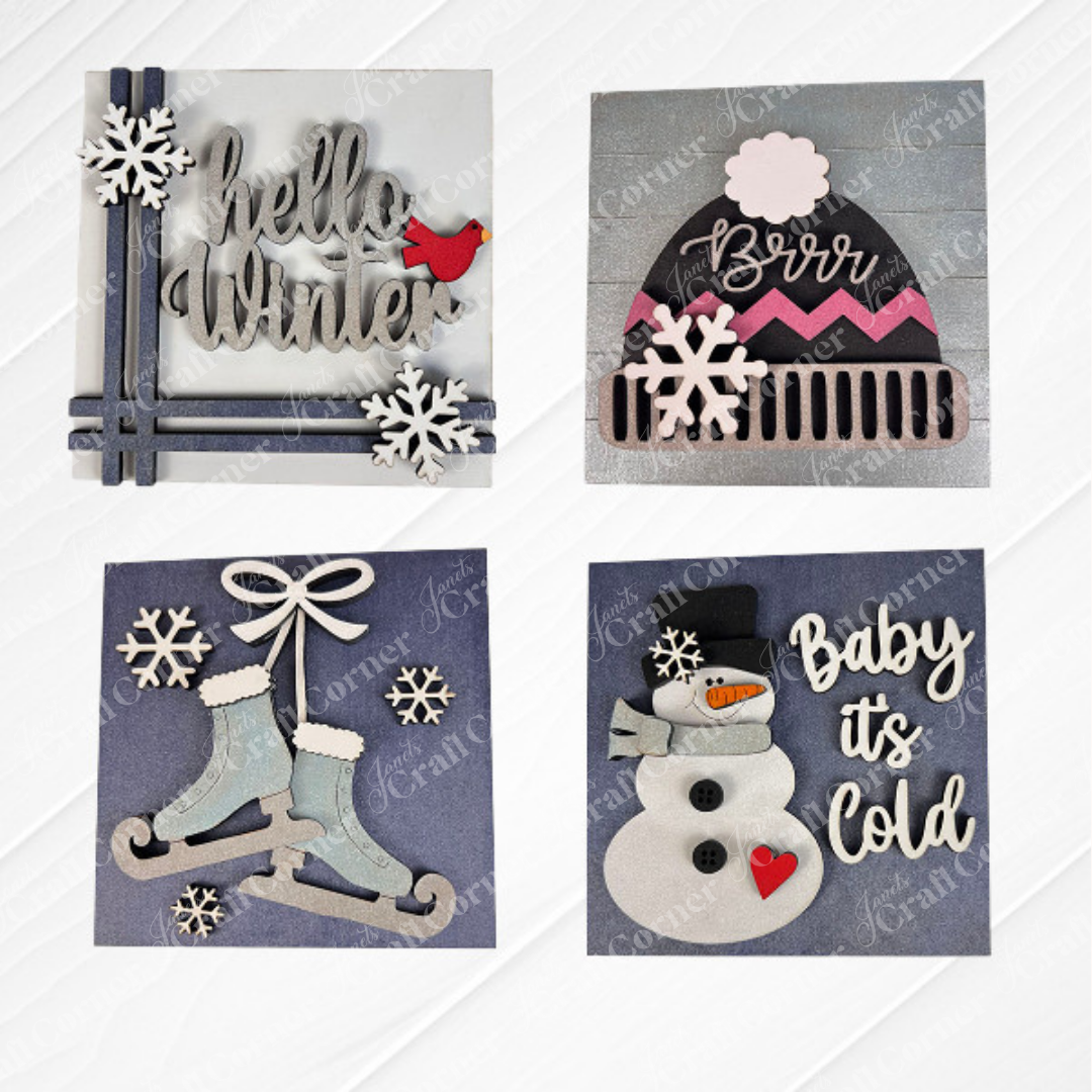 Janet's Craft Corner's Hello Winter Squares set includes four winter-themed tiered tray signs: "Hello Winter" with snowflakes and a red bird, a "Brrr" hat, ice skates, and a snowman—ideal for seasonal decor or DIY crafting.