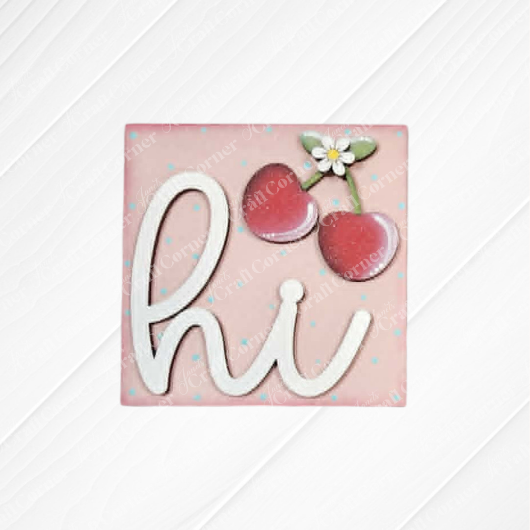 Janet's Craft Corner Cherry Squares DIY kit: pink square wood cut-out with "hi" in white script, two red cherries, and a white flower at the top right. Subtle diagonal background—perfect for tiered tray decor.