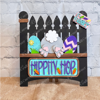 Janet's Craft Corner offers a charming DIY home decor kit featuring a bunny bottom, colorful eggs, a "Hippity Hop" sign with carrots, and an "Easter" tag on burlap. This Garden Fence with Insert includes a black picket fence and interchangeable inserts for endless creativity.