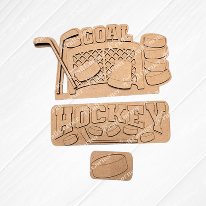 The Hockey Interchangeable Insert DIY home decor kit by Janet's Craft Corner features wooden cutouts with hockey-themed designs arranged on a textured surface. Included in the kit are cutouts of crossed hockey sticks, a goal net, pucks, and the words "GOAL" and "HOCKEY," making it ideal for creating interchangeable home decorations.