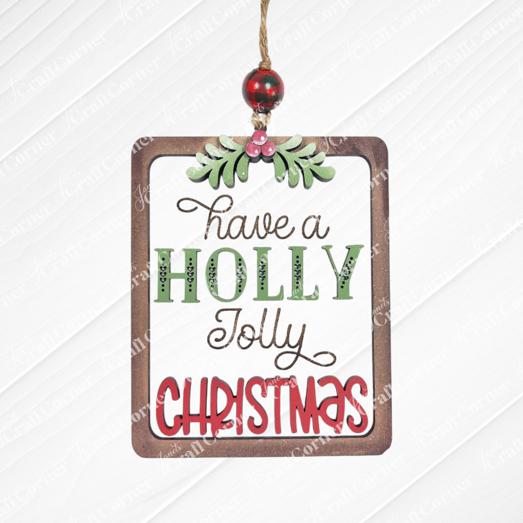 Add festive cheer with Janet's Craft Corner Santa Ornaments DIY holiday craft kit—a rectangular ornament featuring "Have a holly jolly Christmas" in green, red, and gold, topped with holly leaves and berries. Set of 1.