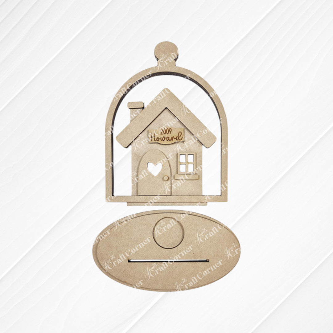 The "Home Cloche Votive Holder Shelf Sitter" by Janet's Craft Corner is a wooden cutout of a house engraved with "Welcome," set in a cloche-shaped frame. It features an oval plaque against a lined white background, perfect for DIY craft kit enthusiasts seeking unique home decor.