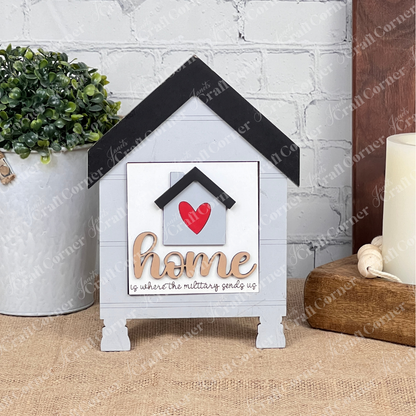 “Military Squares” by Janet’s Craft Corner is a decorative house-shaped wood sign with a heart, “home,” and “is where the military sends us”—perfect for tray or tabletop decor alongside your favorite plant and candle.
