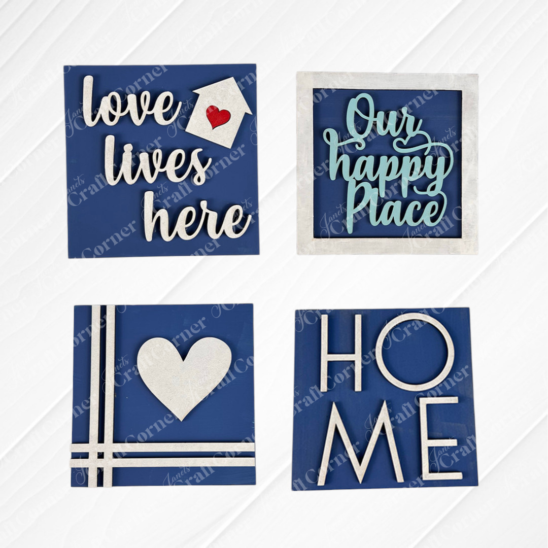 Add charm to any space with Janet's Craft Corner Home Squares—four decorative blue wood pieces for tiered trays: "love lives here" (house), "Our happy Place" (frame), heart with lines, and "HOME" with a heart-shaped "O".