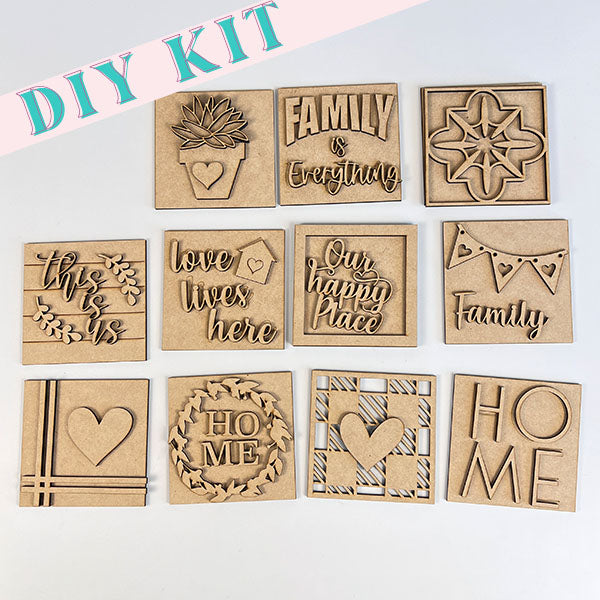 The Home Family Interchangeable Squares kit from Janet's Craft Corner contains various wooden plaque designs that serve as mini signs. These plaques include phrases such as "Family is Everything," "Love Lives Here," and "Our Happy Place," complemented by heart and decorative patterns, making them a charming addition to your home decor.