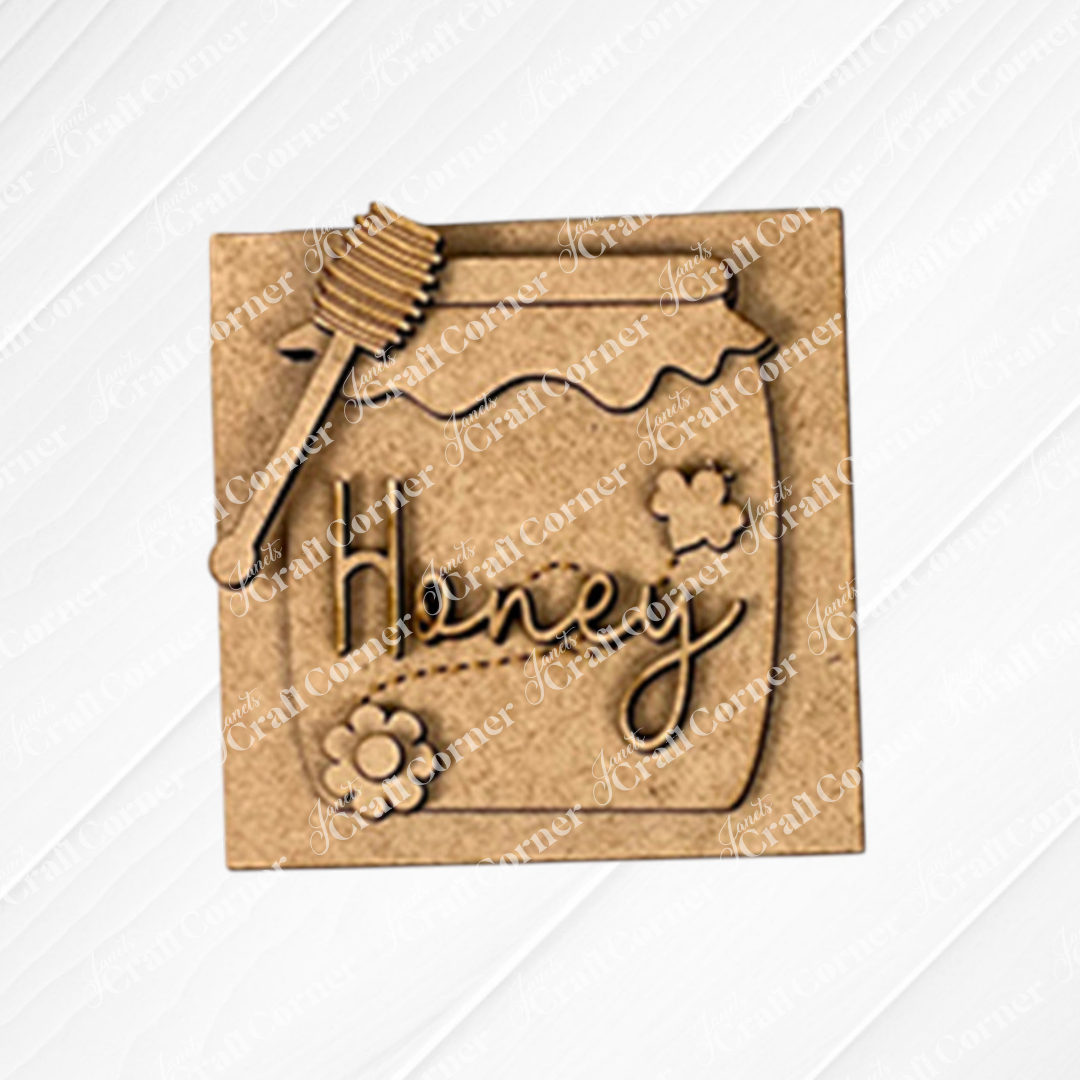 The Bee Swappable Squares DIY kit by Janet's Craft Corner includes the honey jar labeled "Honey,"  - displayed on a white wood background.