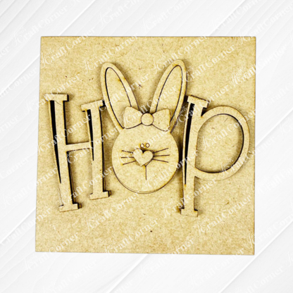 Janet's Craft Corner’s Easter Bunny Squares: wood sign with "HOP," the "O" as a bunny face—long ears, bow, heart nose. Charming cut-out for tiered tray décor, set on a light textured background.