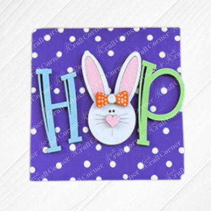 Janet's Craft Corner Easter Bunny Squares feature the word "HOP" on a purple polka-dot background, with a bunny-face "O" complete with pink ears, heart nose, and orange bow—ideal for tiered tray Easter decor.