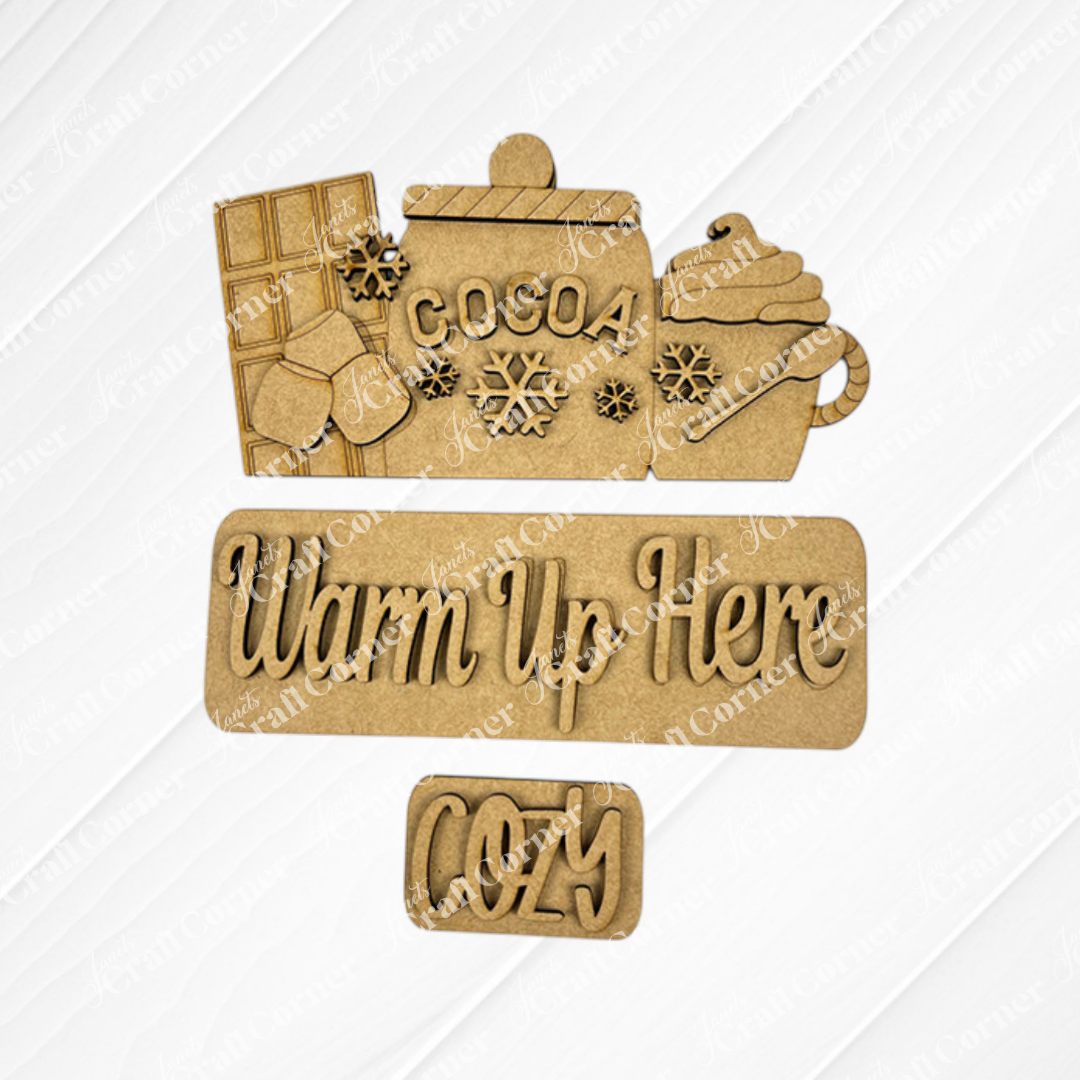 The Hot Cocoa Interchangeable Insert DIY home décor kit from Janet's Craft Corner is perfect for enhancing your home décor. It includes charming wooden cutouts depicting a cocoa jar with marshmallows and whipped cream, a chocolate bar, snowflakes, and the words "Warm Up Here" and "Cozy," making it ideal for any DIY craft project.