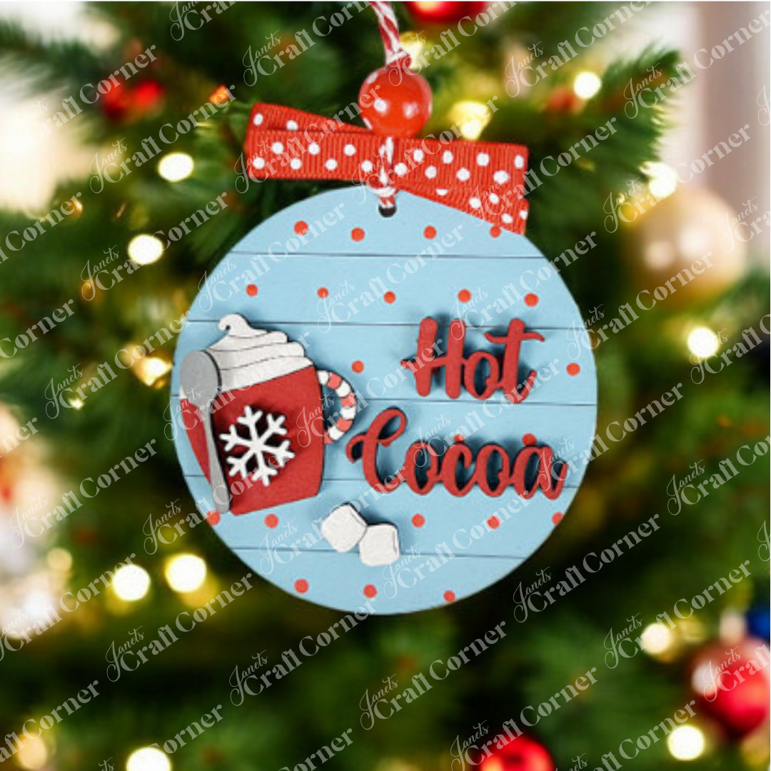 Craft a cozy scene with Janet's Craft Corner's Hot Cocoa Round Ornament. This DIY kit features a festive cup of cocoa with whipped cream, a candy cane, and snowflake against a blue backdrop with red spots. Finished with a red ribbon and blurred holiday lights, it adds warmth to any setting.
