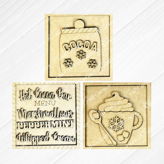 Janet's Craft Corner Hot Cocoa Squares are DIY decor kits with three laser-cut wooden pieces: a snowflake cocoa mug, a "Hot Cocoa Bar Menu" sign, and a steaming cup with whipped cream and snowflake details.