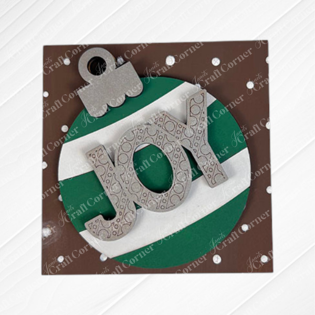 Add a festive touch with Janet's Craft Corner Christmas Icon Swappable Squares—the DIY seasonal home decor craft kit featuring green-and-white striped ornament designs, "JOY" in silver letters, and charming holiday accents.