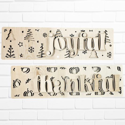 The Reversible Thankful/Joyful Chunky Shelf Sitter from Janet's Craft Corner makes a charming addition to your home décor. One side of this festive sign features the word "joyful," accompanied by snowflakes, trees, and bells. Flip it over for a "thankful" message beautifully surrounded by pumpkins. This DIY home decor craft kit is perfect for displaying against a white brick background.