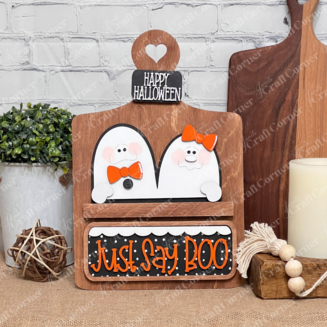 Janet's Craft Corner's Just Say Boo Interchangeable Insert craft kit includes two ghost with orange bows and signs that say "Just Say Boo" and "Happy Halloween"—perfect DIY Halloween decor or insert for your home, featuring three cute pieces displayed on a stained breadboard base.