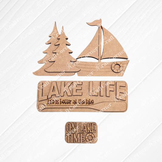Janet's Craft Corner Lake Life Interchangeable Insert is a DIY craft kit featuring 3 wooden pieces—two pine trees, a sailboat, and two signs with "Lake Life" phrases—perfect for seasonal home decor.