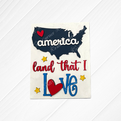 Janet’s Craft Corner Patriotic Farmhouse Signs kit features a dark blue USA map with “america” and a red heart, plus “land that I Love” (heart-shaped "o") with yellow stars—ideal for tiered trays or seasonal DIY home decor. Set of 1.