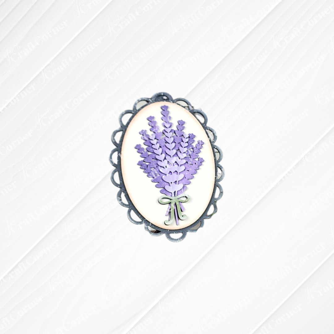 The Lavender Decor Set by Janet's Craft Corner features an oval brooch with purple lavender flowers and a green ribbon on a white background with a silver border—ideal for DIY projects or as an accent for your lavender mini sign.