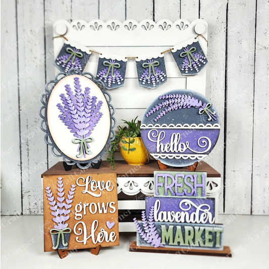 Janet's Craft Corner’s Lavender Decor Set includes farmhouse-style signs with phrases like “hello,” “Fresh lavender market,” and “Love grows here,” a plant, and garland on a white wood background—perfect for DIY home decor.