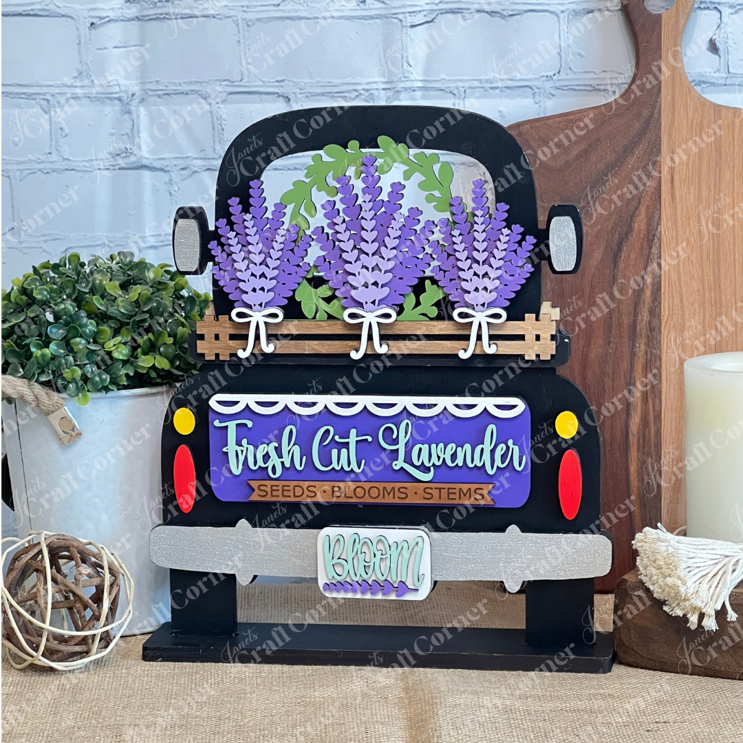 The Lavender Interchangeable Insert – DIY Craft Kit by Janet's Craft Corner features a decorative black truck with lavender bunches and a "Fresh Cut Lavender: Seeds • Blooms • Stems" sign, perfect for charming farmhouse-style home décor.