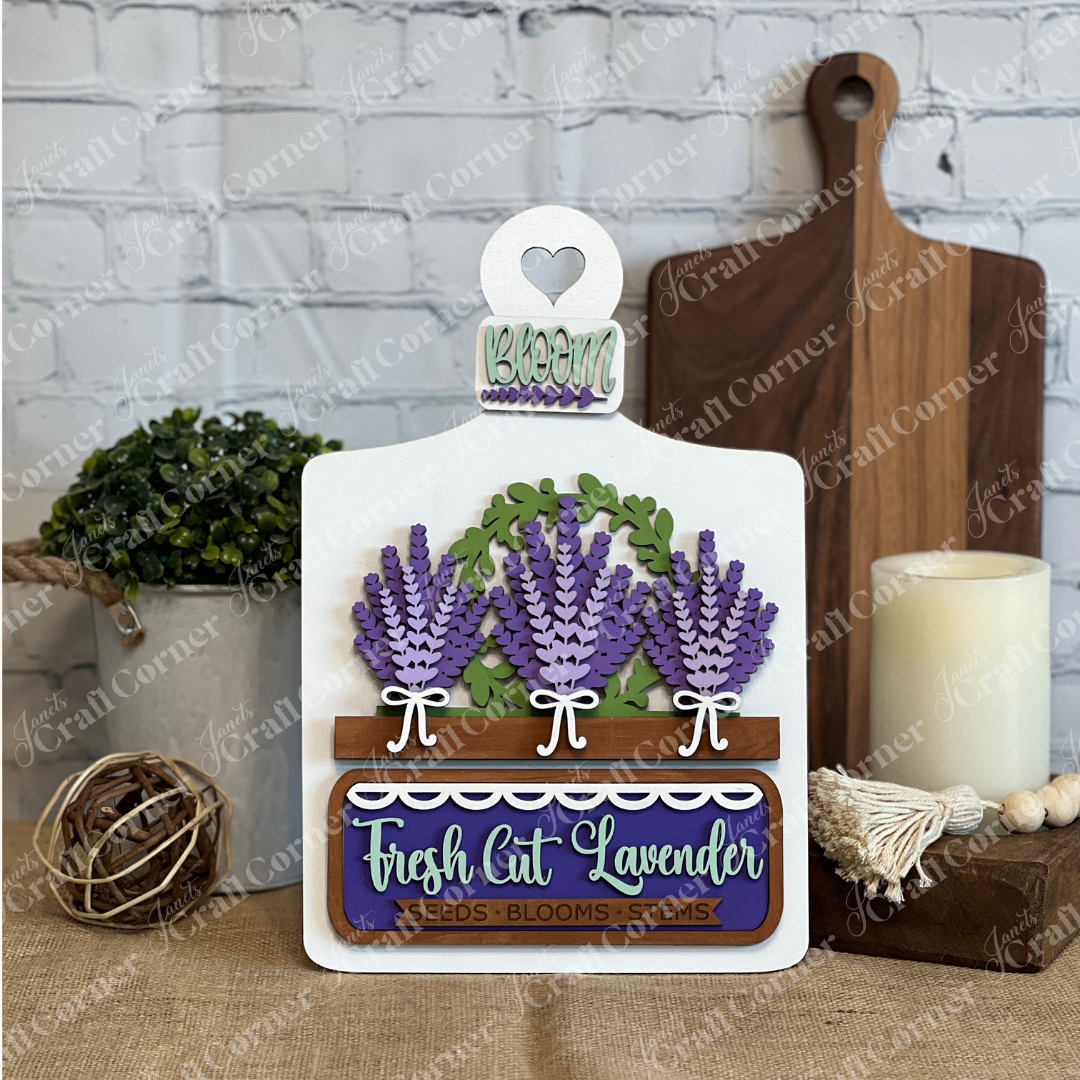 The Lavender Interchangeable Insert DIY Craft Kit by Janet's Craft Corner features 3D purple lavender, green leaves, and a “Fresh Cut Lavender” label. Ideal for farmhouse or lavender home décor. Home decor items shown in background.