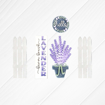 Janet's Craft Corner Lavender Interchangeable Porch Set features a garden-inspired DIY display with a circular "hello" sign, vertical "lavender farm fresh" sign, potted lavender, and four white picket fence pieces.