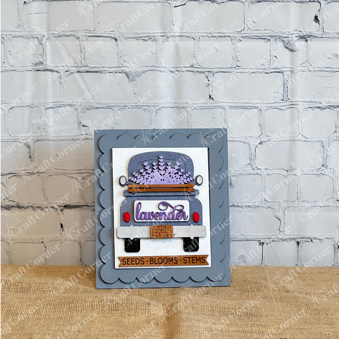 Janet’s Craft Corner’s Lavender Switchable Farmhouse Signs DIY Craft Kit includes handmade cards with blue trucks, lavender blooms, a farmhouse sign, scalloped gray background, gold border, and a “SEEDS • BLOOMS • STEMS” label for cozy house décor.