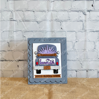 Janet’s Craft Corner’s Lavender Switchable Farmhouse Signs DIY Craft Kit includes handmade cards with blue trucks, lavender blooms, a farmhouse sign, scalloped gray background, gold border, and a “SEEDS • BLOOMS • STEMS” label for cozy house décor.
