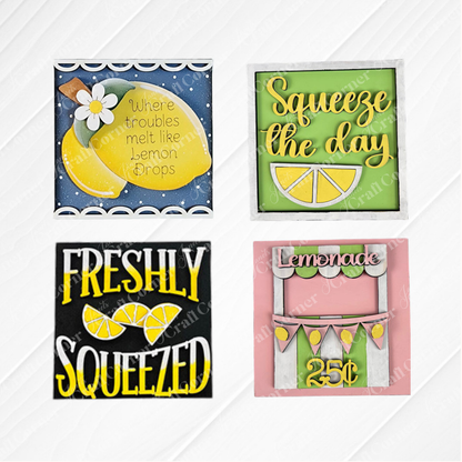 Lemon Squares by Janet's Craft Corner is a DIY kit with four colorful signs featuring lemon-themed designs and phrases: “Where troubles melt like lemon drops,” “Squeeze the day,” “Freshly squeezed,” and a lemonade stand with “Lemonade 25¢.”.