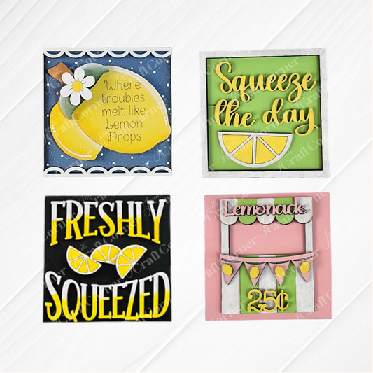 Lemon Squares by Janet's Craft Corner is a DIY kit with four colorful signs featuring lemon-themed designs and phrases: “Where troubles melt like lemon drops,” “Squeeze the day,” “Freshly squeezed,” and a lemonade stand with “Lemonade 25¢.”.