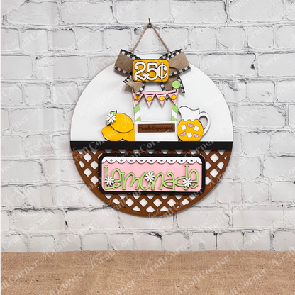 Janet's Craft Corner presents the Lemonade Interchangeable Insert, a delightful round door hanger DIY home decor kit. Featuring a lemonade theme with a pitcher of refreshing lemonade, fresh lemons, and a "Fresh Squeezed" sign, it's topped with a charming burlap and checkered ribbon bow. This hand-painted craft kit is perfect for any season due to its interchangeable insert feature.