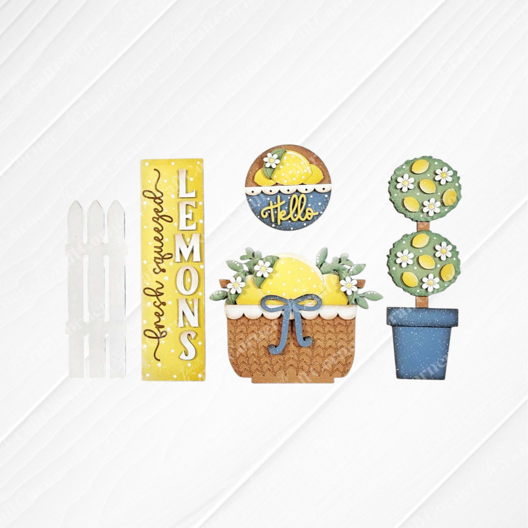 The Lemons Interchangeable Porch Set by Janet's Craft Corner features decorative signs—a white fence, yellow "fresh squeezed LEMONS," "hello" bowl, lemon basket with bow, and potted topiary—perfect for DIY seasonal home decor.
