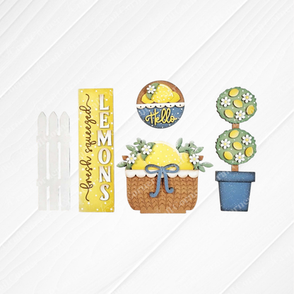 The Lemons Interchangeable Porch Set by Janet's Craft Corner features decorative signs—a white fence, yellow "fresh squeezed LEMONS," "hello" bowl, lemon basket with bow, and potted topiary—perfect for DIY seasonal home decor.