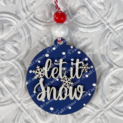 Elevate your festive decorations with Janet's Craft Corner's Round Christmas Ornament DIY Decoration Kit. This lovely round blue ornament, adorned with white polka dots and snowflakes, displays the cheerful message "let it snow." It elegantly hangs from a red and white string embellished with matching beads, making it a charming addition to your decorative white surface.