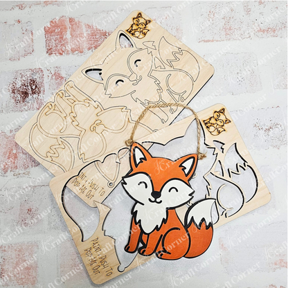 Two Little Fox Kids Pop-Out puzzles by Janet's Craft Corner—one fully assembled as an orange and white fox, the other shown in pieces. Both feature engraved outlines/text, making a charming DIY holiday decor or Trim a Tree craft kit for kids.