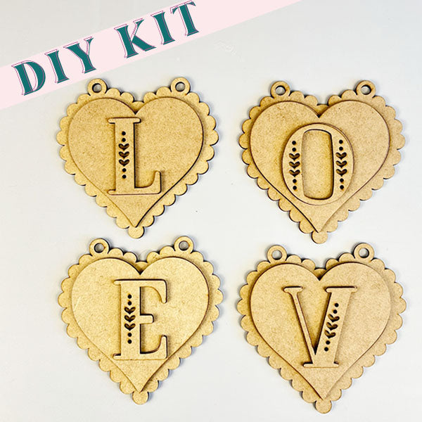 Introducing the L-O-V-E Banner from Janet's Craft Corner, a delightful craft kit that includes four heart-shaped wooden ornaments. Each ornament features a letter to spell "LOVE," adorned with intricate vine details. Ideal for home décor, this DIY kit comes with easy-to-follow instructions to help you add a personalized touch to your space.