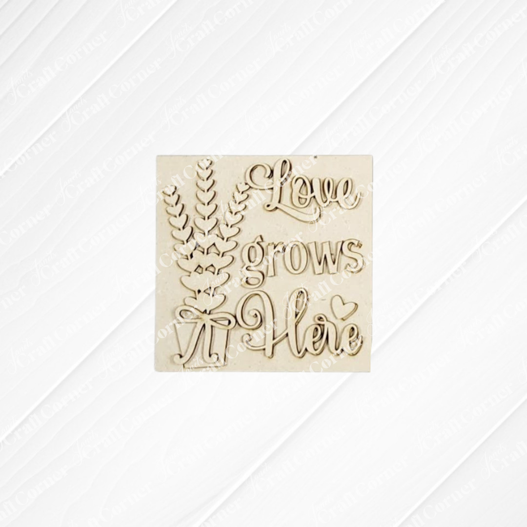The Lavender Decor Set from Janet's Craft Corner features a light wood plaque with "Love grows Here," accented by decorative leaves, a bow, and a pale background—perfect for DIY farmhouse charm and seasonal home decor.