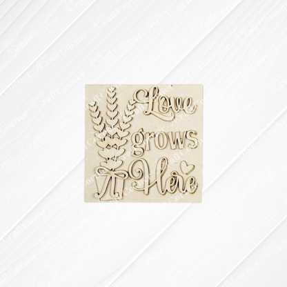 The Lavender Decor Set from Janet's Craft Corner features a light wood plaque with "Love grows Here," accented by decorative leaves, a bow, and a pale background—perfect for DIY farmhouse charm and seasonal home decor.