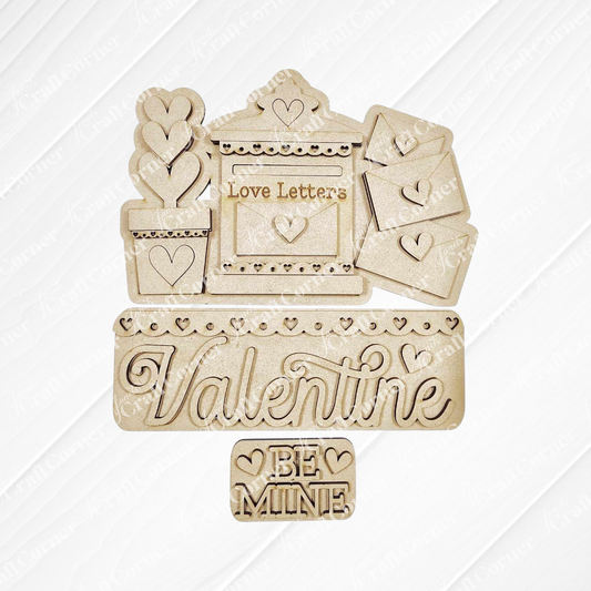 Janet's Craft Corner presents the Love Letters Interchangeable Insert: hand-painted wooden Valentine's cutouts including a "Love Letters" mail slot, a "Valentine" sign, and a "Be Mine" plaque with heart details on burlap over a textured white background.