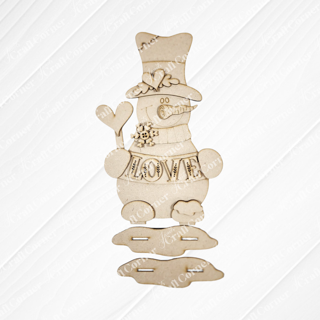 Janet's Craft Corner Valentine Snowmen Decor Set is a DIY seasonal home decor craft kit featuring wooden snowmen with top hats, scarves, and engraved “LOVE” hearts—ideal for winter decorating or creative crafting projects.