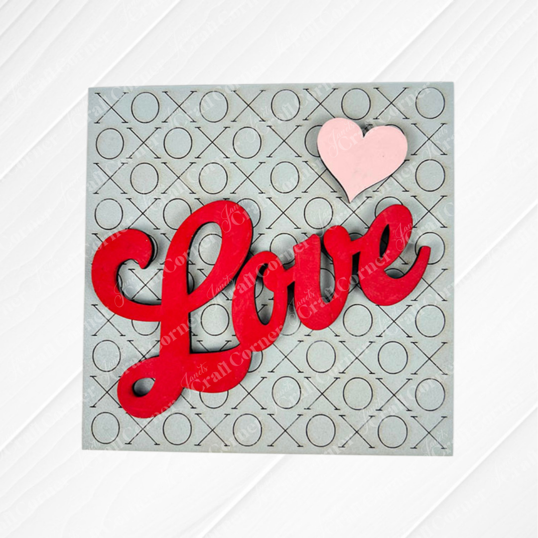 Love Squares by Janet's Craft Corner features "Love" in bold red script with a pink heart on a gray background with X and O pattern—ideal for DIY seasonal decor or as an accent to swappable square signs.