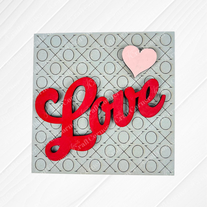 Love Squares by Janet's Craft Corner features "Love" in bold red script with a pink heart on a gray background with X and O pattern—ideal for DIY seasonal decor or as an accent to swappable square signs.