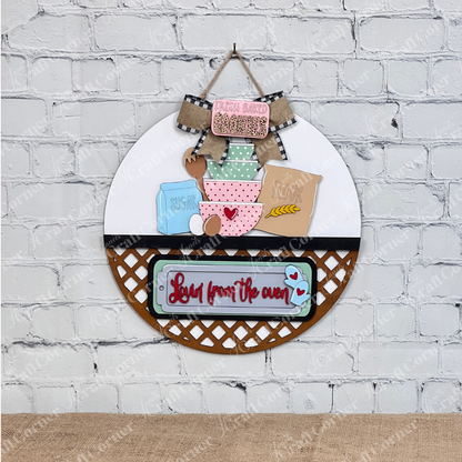 Janet's Craft Corner offers the Lovin from the Oven Interchangeable Insert DIY home decor craft kit, featuring round wall decor with labels "Fresh Baked," "Sugar," "Flour," and more. Enhanced with a gingham bow, lattice detail, and set against a whitewashed brick wall—perfect for DIY enthusiasts!.