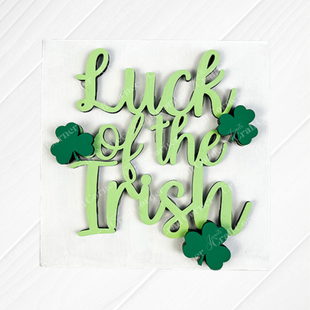Janet's Craft Corner's Lucky Irish Squares features green “Luck of the Irish” script and three shamrocks on a white wood background—ideal tiered tray decor or to pair with Swappable Squares wood cut-outs.