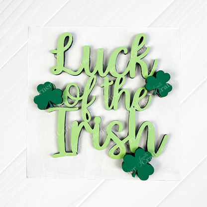 Janet's Craft Corner's Lucky Irish Squares features green “Luck of the Irish” script and three shamrocks on a white wood background—ideal tiered tray decor or to pair with Swappable Squares wood cut-outs.
