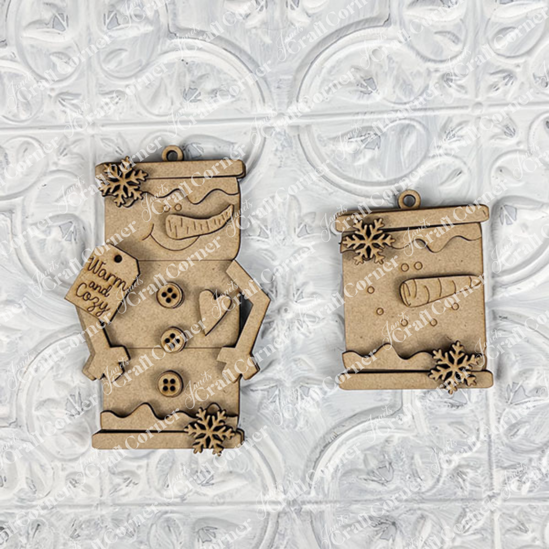 Janet's Craft Corner Snowman Ornaments—DIY holiday craft kit (Set of 1)—feature two unfinished wooden designs, including a snow globe and “Warm and Cozy” sign, perfect for festive décor or creative holiday projects.