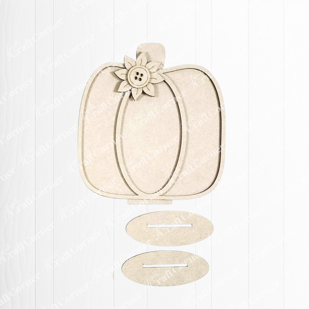 The Fall Harvest Mini Shelf Sitters by Janet's Craft Corner is a wooden pumpkin-shaped DIY craft kit with floral and button detail, ideal for autumn decor. Includes two oval slotted pieces, shown on a white wooden background. Set of 1.