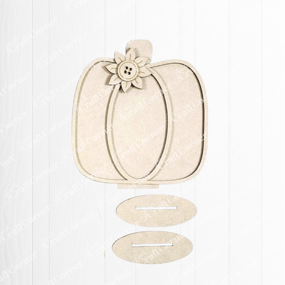 The Fall Harvest Mini Shelf Sitters by Janet's Craft Corner is a wooden pumpkin-shaped DIY craft kit with floral and button detail, ideal for autumn decor. Includes two oval slotted pieces, shown on a white wooden background. Set of 1.