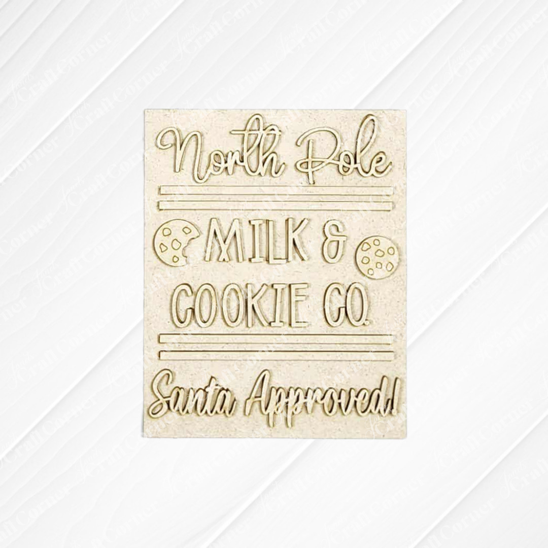 The North Pole Switchable Farmhouse Sign by Janet's Craft Corner features “North Pole Milk & Cookie Co. Santa Approved!” with cookie illustrations on a textured background—perfect for festive DIY holiday home decor.