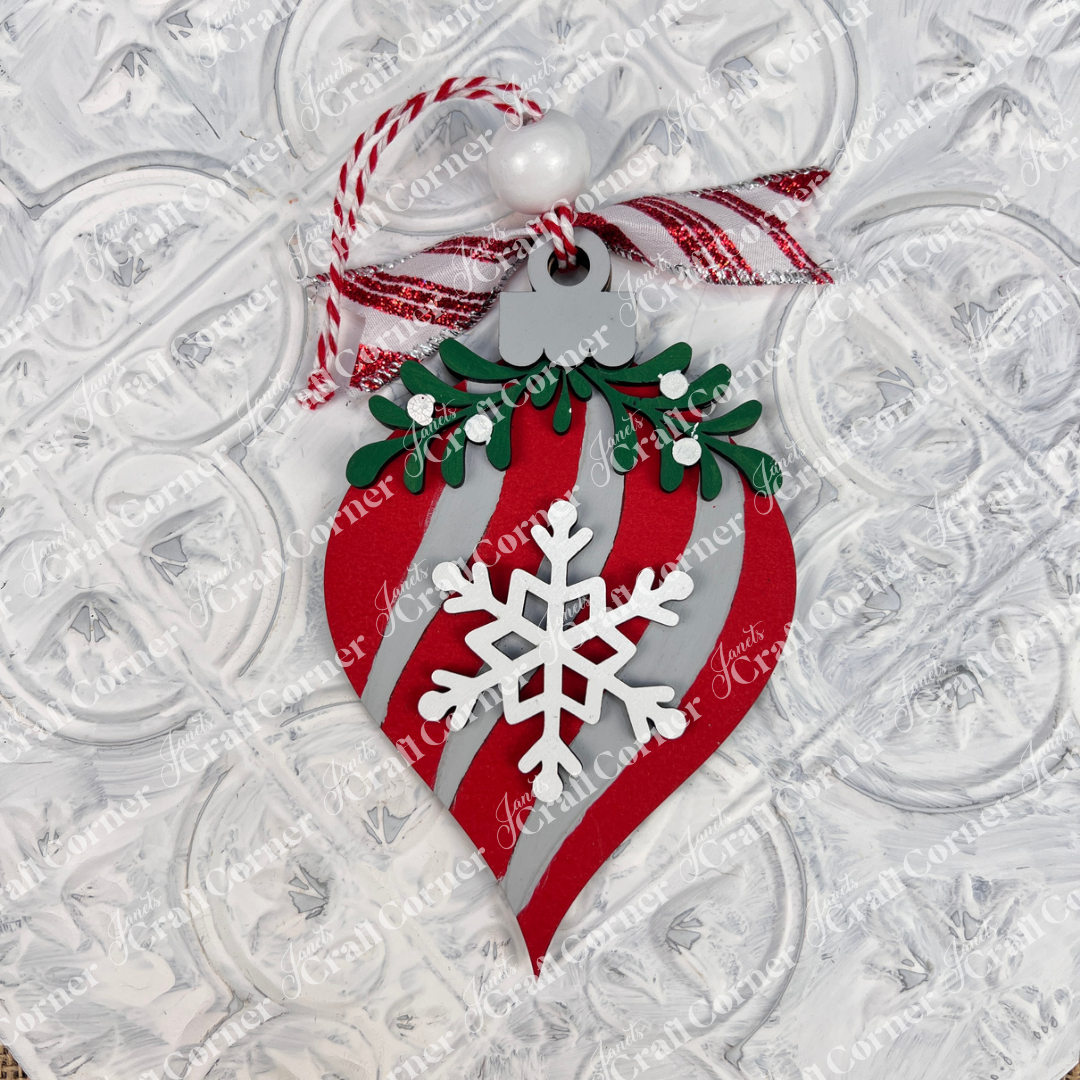 The Mistletoe Ornaments DIY Decor Kit by Janet's Craft Corner includes 6 red and white striped ornaments with snowflake centers, green holly leaves, red berries, white beads, and red-striped strings—perfect for festive decorating.