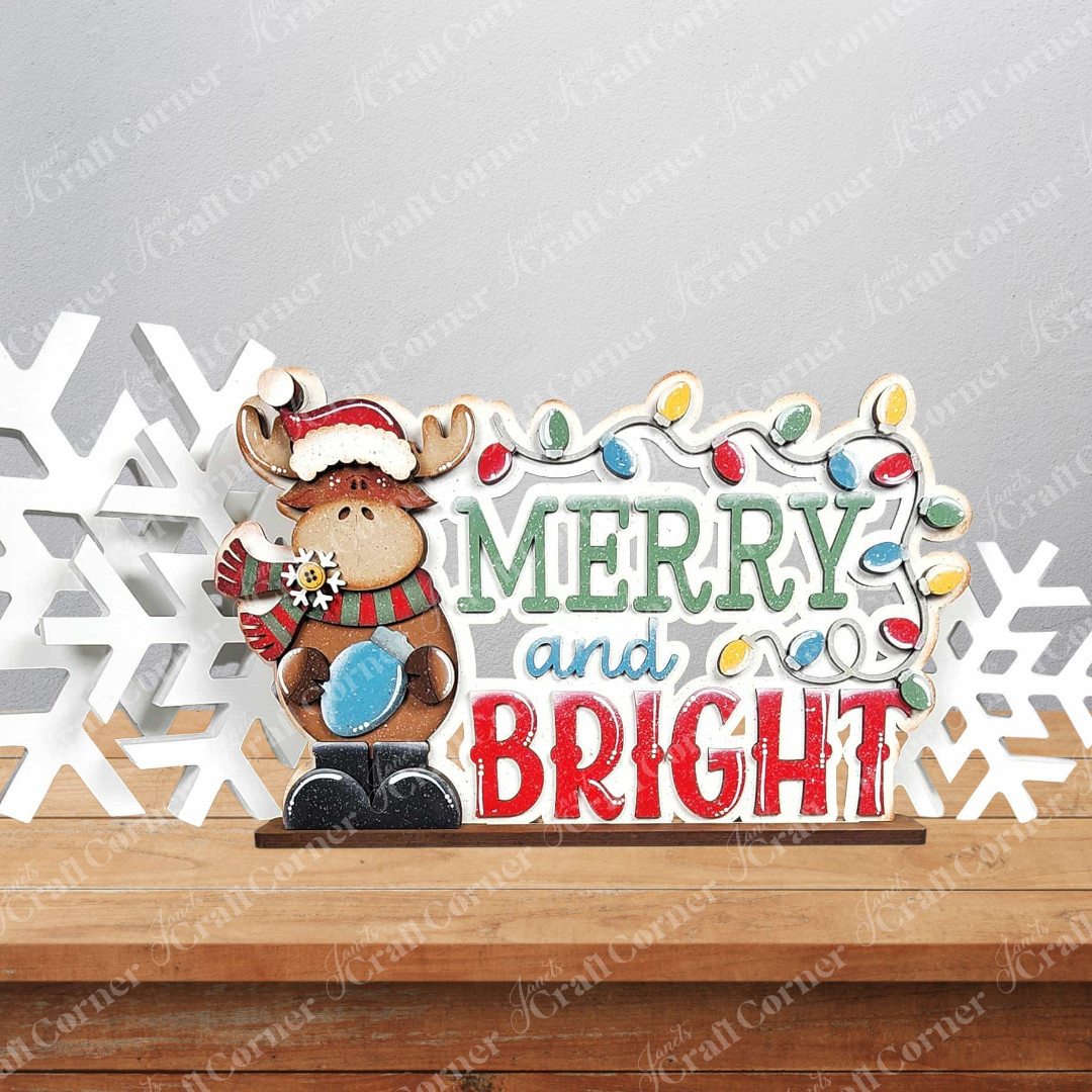 Janet's Craft Corner Moose Merry and Bright Word Art Shelf Sitter is a DIY seasonal home decor craft kit featuring a festive moose design, perfect for woodland-themed holiday decorating. Set of 1.